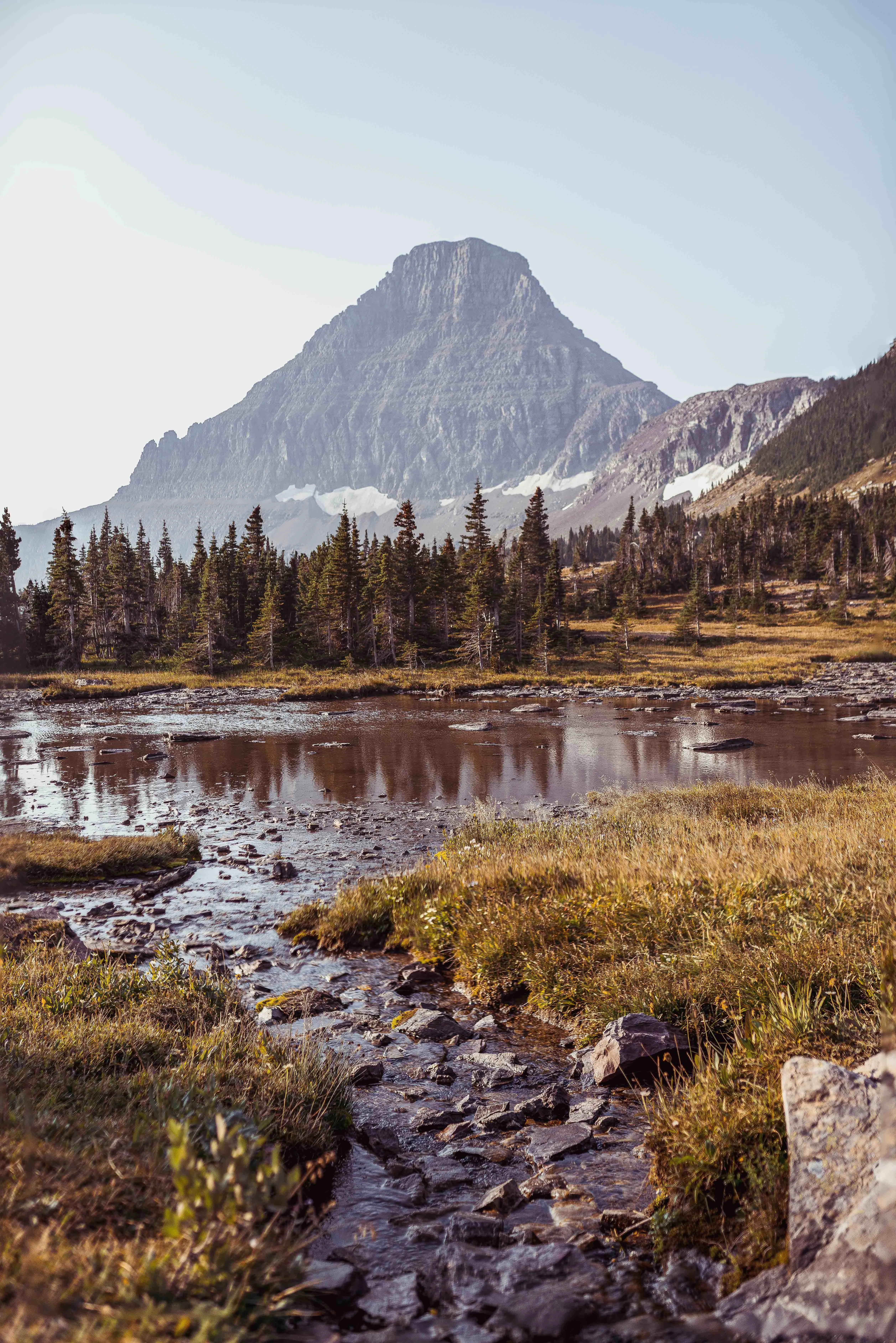 Thomas McClure landscape photography of a mountain stream leading to a snow-capped peak in Glacier National Park