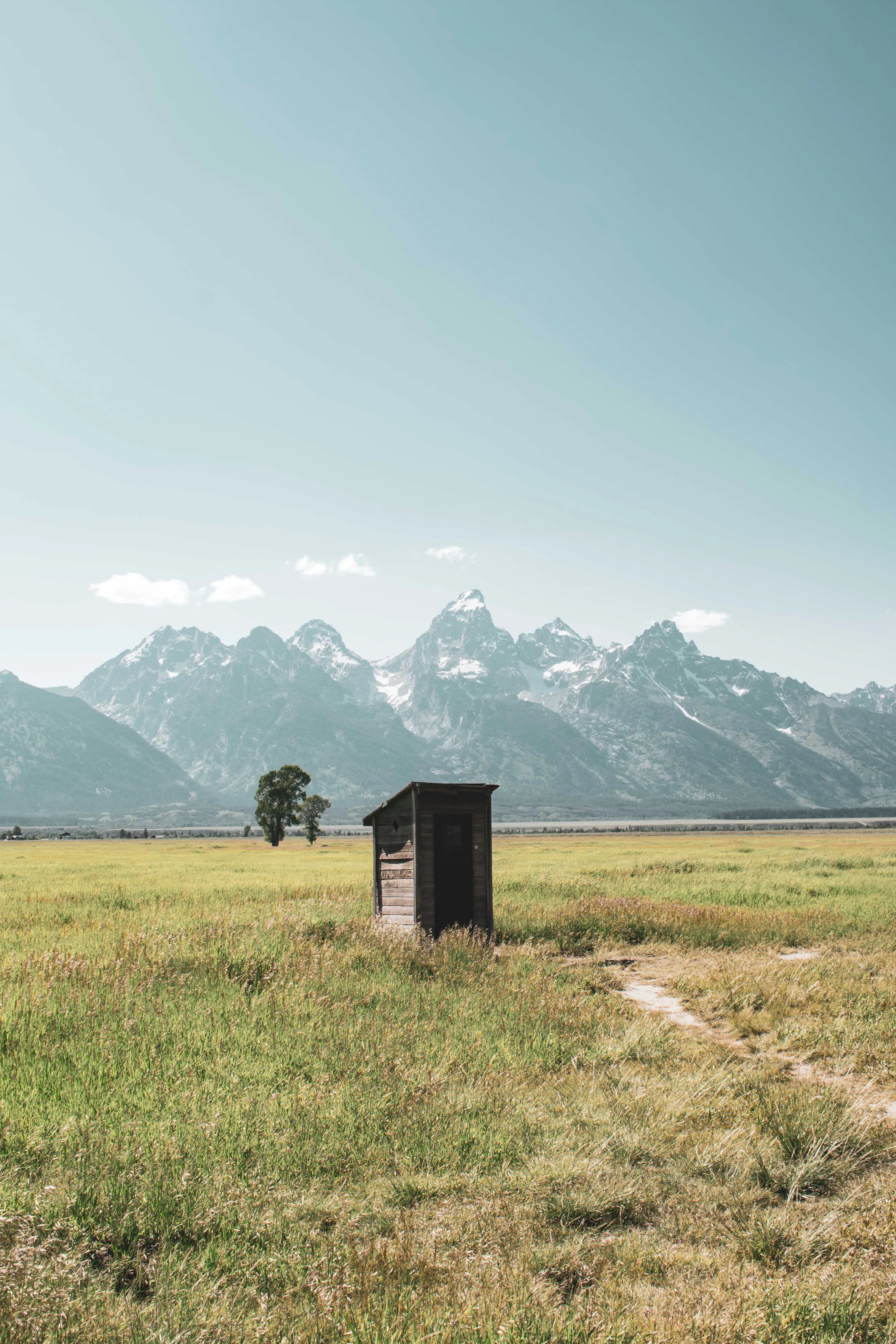 Landscape photography by Thomas McClure of a rustic wooden barn with the Grand Teton mountain range towering behind in Wyoming